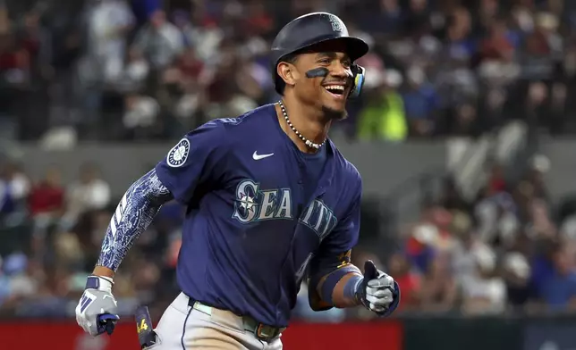 Seattle Mariners' Julio Rodriguez reacts toward the dugout as he runs the bases after hitting a two-run home run against the Texas Rangers in the seventh inning of a baseball game Friday, Sept. 20, 2024, in Arlington, Texas. (AP Photo/Richard W. Rodriguez)