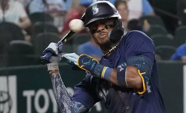 Seattle Mariners' Julio Rodríguez is brushed back by a high inside pitch during the sixth inning of a baseball game against the Texas Rangers, Saturday, Sept. 21, 2024, in Arlington, Texas. (AP Photo/LM Otero)