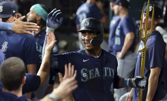 Seattle Mariners' Julio Rodriguez celebrates in the dugout after a two-run home run against the Texas Rangers in the seventh inning of a baseball game Friday, Sept. 20, 2024, in Arlington, Texas. (AP Photo/Richard W. Rodriguez)