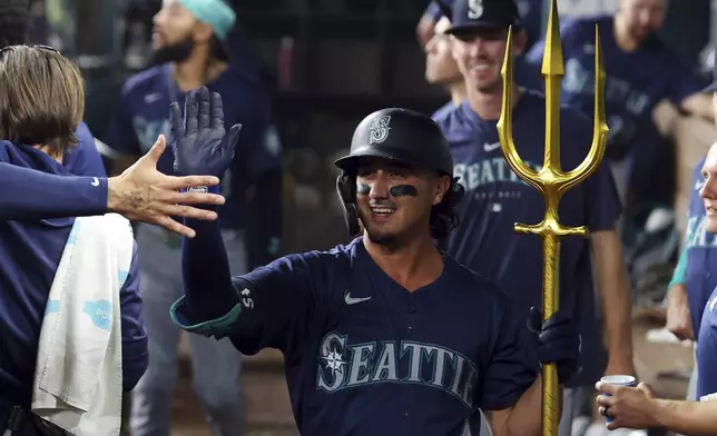 Seattle Mariners Josh Rojas (4) celebrates in the dugout after a solo home run against the Texas Rangers in the third inning of a baseball game, Friday, Sept. 20, 2024, in Arlington, Texas. (AP Photo/Richard W. Rodriguez)