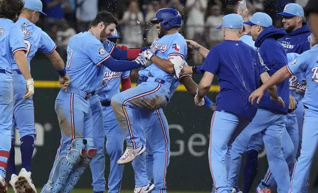 Texas Rangers' Marcus Semien, center, is congratulated by teammates after hitting a single that scored Leody Taveras during the ninth inning of a baseball game against the Seattle Mariners, Sunday, Sept. 22, 2024, in Arlington, Texas.(AP Photo/LM Otero)