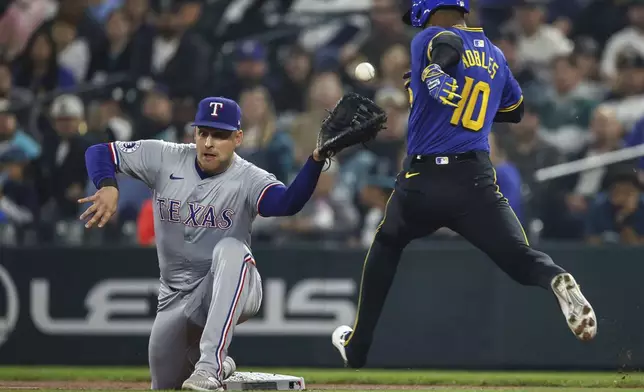 Texas Rangers first baseman Nathaniel Lowe, left, cannot pull down a throw from third baseman Josh Jung in the first inning, allowing Seattle Mariners' Victor Robles to reach first safely during a baseball game Friday, Sept. 13, 2024, in Seattle. (Dean Rutz/The Seattle Times via AP)