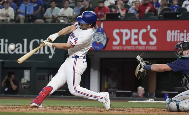 Texas Rangers' Josh Smith homers, left, in front of Seattle Mariners catcher Cal Raleigh during the third inning of a baseball game Saturday, Sept. 21, 2024, in Arlington, Texas. (AP Photo/LM Otero)