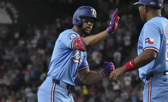 Texas Rangers' Leody Taveras, left, is congratulated by third base coach Tony Beasley, right, after hitting a home run during the seventh inning of a baseball game against the Seattle Mariners, Sunday, Sept. 22, 2024, in Arlington, Texas. (AP Photo/LM Otero)