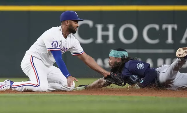 Texas Rangers second base Marcus Semien, left, tags Seattle Mariners' J.P. Crawford out at second base as Crawford tries to the stretch a single into a double during the sixth inning of a baseball game, Saturday, Sept. 21, 2024, in Arlington, Texas. (AP Photo/LM Otero)