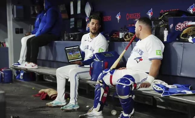 Toronto Blue Jays pitcher Jose Berrios, center, talks over video with catcher Alejandro Kirk, right, during second-inning baseball game action against the Miami Marlins in Toronto, Friday, Sept. 27, 2024. (Chris Young/The Canadian Press via AP)