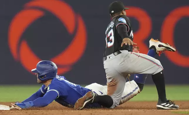 Toronto Blue Jays' George Springer, left, steals second base past Miami Marlins shortstop Xavier Edwards, right, during third-inning baseball game action in Toronto, Saturday, Sept. 28, 2024. (Chris Young/The Canadian Press via AP)