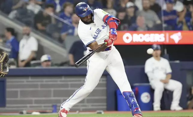 Toronto Blue Jays' Vladimir Guerrero Jr. hits a sacrifice fly, scoring Jonatan Clase, during sixth-inning baseball game action against the Miami Marlins in Toronto, Friday, Sept. 27, 2024. (Chris Young/The Canadian Press via AP)