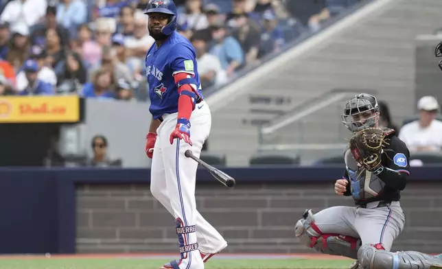 Toronto Blue Jays designated hitter Vladimir Guerrero Jr., left, tosses his bat after being walked by Miami Marlins pitcher Ryan Weathers as Marlins catcher Nick Fortes,right, looks on during first-inning baseball game action in Toronto, Sunday, Sept. 29, 2024. (Chris Young/The Canadian Press via AP)