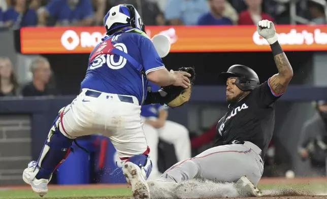 Miami Marlins' Dane Myers is tagged out at home plate by Toronto Blue Jays catcher Alejandro Kirk during sixth inning interleague MLB baseball action in Toronto, Saturday, September 28, 2024. (Chris Young/The Canadian Press via AP)