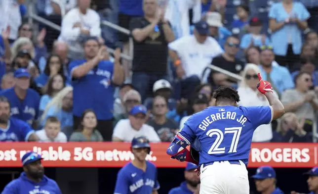 Toronto Blue Jays designated hitter Vladimir Guerrero Jr. (27) gestures as he walks back to the dugout after after being walked by Miami Marlins pitcher Lake Bachar and being replaced by pinch runner Nathan Lukes during eighth-inning baseball game action in Toronto, Sunday, Sept. 29, 2024. (Chris Young/The Canadian Press via AP)