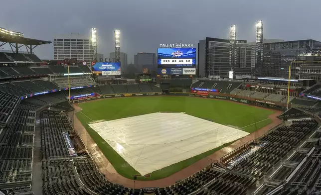 A tarp covers the infield as rain comes down at Truist Park after the baseball game between the New York Mets and Atlanta Braves as postponed, Wednesday, Sept. 25, 2024, in Atlanta. The Mets-Braves games scheduled for Wednesday and Thursday are postponed and will be made up as a doubleheader Monday, Sept. 30. (AP Photo/Jason Allen)