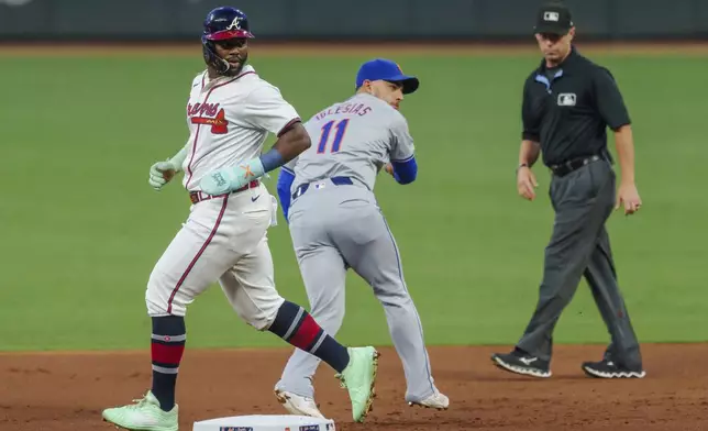 New York Mets second baseman Jose Iglesias, center, tags Atlanta Braves' Michael Harris II, left, out at second base and then attempts to throw out Ozzie Albies (1) at first base in the first inning of a baseball game, Tuesday, Sept. 24, 2024, in Atlanta. (AP Photo/Jason Allen)