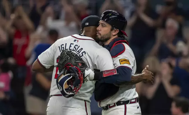 Atlanta Braves pitcher Raisel Iglesias, left, celebrates the win with catcher Travis d'Arnaud, right, following the ninth inning of a baseball game against the New York Mets, Tuesday, Sept. 24, 2024, in Atlanta. (AP Photo/Jason Allen)