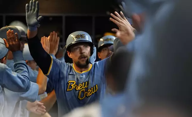 Milwaukee Brewers' Rhys Hoskins is congratulated in the dugout after hitting a grand slam during the first inning of a baseball game against the New York Mets, Friday, Sept. 27, 2024, in Milwaukee. (AP Photo/Aaron Gash)