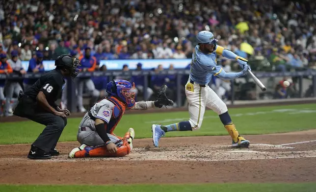 Milwaukee Brewers' Jackson Chourio, right, hits an RBI-single during the fourth inning of a baseball game against the New York Mets, Friday, Sept. 27, 2024, in Milwaukee. (AP Photo/Aaron Gash)