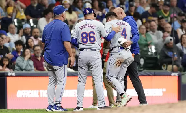 New York Mets' Francisco Alvarez (4) exits the field with coaches and trainers after suffering an injury at third base during the seventh inning of a baseball game against the Milwaukee Brewers, Friday, Sept. 27, 2024, in Milwaukee. (AP Photo/Aaron Gash)