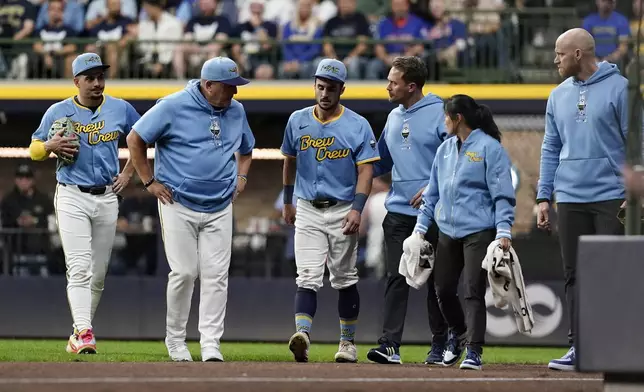 Milwaukee Brewers' Sal Frelick, center, walks off the field during the third inning of a baseball game against the New York Mets, Friday, Sept. 27, 2024, in Milwaukee. Frelick left the game after suffering an injury. (AP Photo/Aaron Gash)