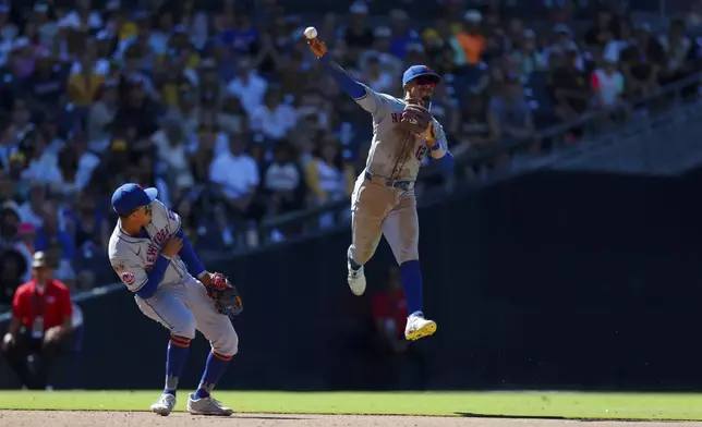 New York Mets shortstop Francisco Lindor, right, makes a jumping throw on a single hit by San Diego Padres' Xander Bogaerts during the eighth inning of a baseball game, Sunday, Aug. 25, 2024, in San Diego. (AP Photo/Brandon Sloter)