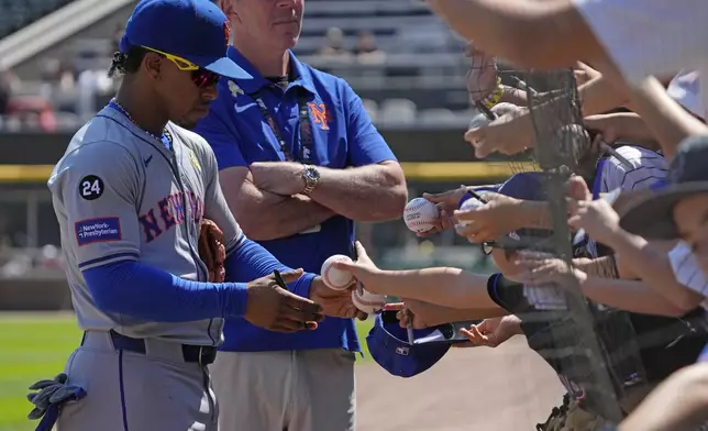 New York Mets' Francisco Lindor, left, returns a ball to a fan after autographing it before a baseball game against the Chicago White Sox in Chicago, Sunday, Sept. 1, 2024. (AP Photo/Nam Y. Huh)