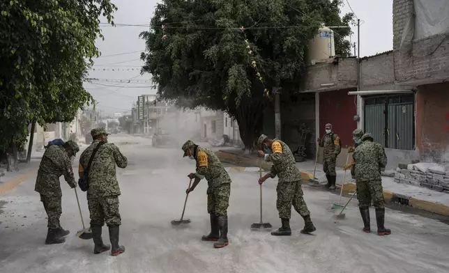 Soldiers clean the streets after applying lime to combat the smell and humidity after sewage-infused flooding in Valle de Chalco, State of Mexico, Monday, 9, 2024. (AP Photo/Felix Marquez)