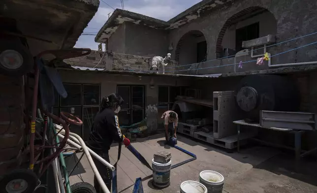 Rosa Daniel, left, helps her neighbor Juana Salazar Segundo move a hose to remove sewage-infused floodwaters from her home in Valle de Chalco, State of Mexico, Thursday, Aug. 29, 2024. (AP Photo/Felix Marquez)