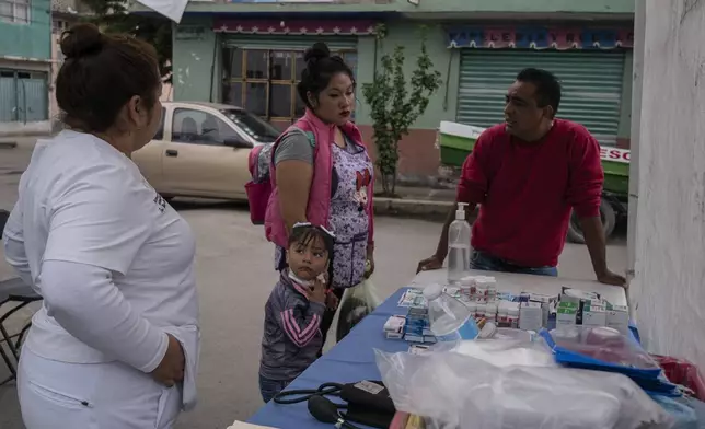 A family approaches medical workers in Valle de Chalco, State of Mexico, who are providing emergency attention during sewage-infused flooding in the area, Thursday, Aug. 29, 2024. (AP Photo/Felix Marquez)