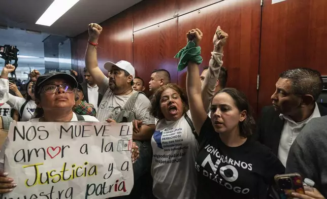 Protesters attempt to break into a Senate room in which lawmakers weigh the government's proposed judicial reform, which would make judges stand for election, in Mexico City, Tuesday, Sept. 10, 2024. (AP Photo/Felix Marquez)