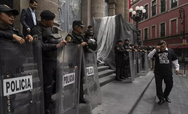 Mexico City legislator, of the National Action Party, Diego Garrido, walks past police who guard the Mexico City Congress amid judicial reform, Thursday, Sept. 12, 2024. (AP Photo/Felix Marquez)