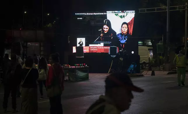 A man walks in front of a screen on which the senatorial vote is broadcast during a protest against government's proposed judicial reform, which would make judges stand for election, outside the Senate in Mexico City, Tuesday, Sept. 10, 2024. (AP Photo/Felix Marquez)