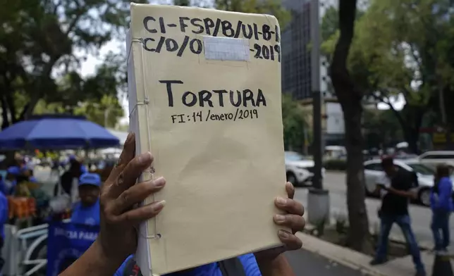 A relative of a prisoner shows a binder alleging their innocence during a rally in support of the government's proposed judicial reform in Mexico City, Wednesday, Sept. 4, 2024. (AP Photo/Felix Marquez)