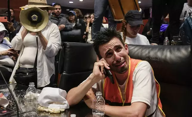 An injured protestor speaks on the phone after breaking into a Senate session in which lawmakers were debating the government's proposed judicial reform, which would make judges stand for election, in Mexico City, Tuesday, Sept. 10, 2024. (AP Photo/Felix Marquez)