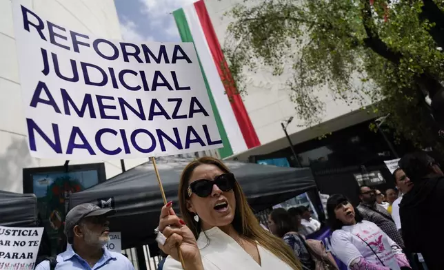 A demonstrator holds the sign "Judicial reform national threat" during a protest outside the Senate against a judicial reform bill in Mexico City, Thursday, Sept. 5, 2024, the day after Congress passed legislation that would require all judges to stand for election. (AP Photo/Felix Marquez)