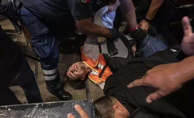 Medics tend to an injured protester after demonstrators broke into the Senate interrupting a debate on the government's proposed judicial reform, which would make judges stand for election, in Mexico City, Tuesday, Sept. 10, 2024. (AP Photo/Felix Marquez)