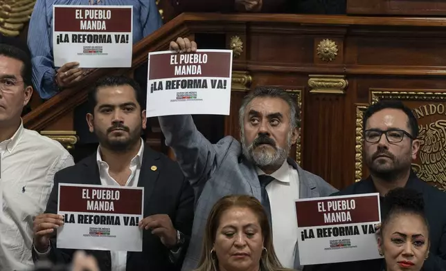 Mexico City legislators in favor of judicial reform hold signs that read in Spanish ¨The people rule. Reform now!¨ at the Mexico City Congress, Thursday, Sept. 12, 2024. (AP Photo/Felix Marquez)