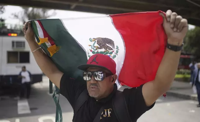 Judicial worker Marcos Arenas holds up a Mexican flag during a protest against constitutional reform proposals that would make judges stand for election, outside a sports center where lawmakers are meeting as an alternative due to other demonstrators blocking Congress in Mexico City, Tuesday, Sept. 3, 2024. (AP Photo/Felix Marquez)