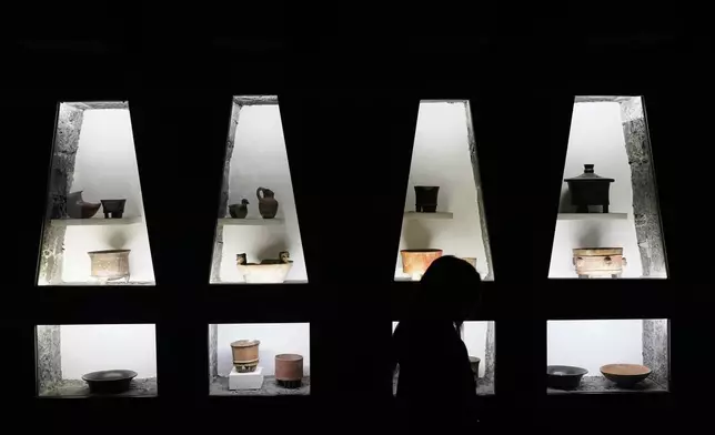 A visitor walks past pre-Hispanic ceramics displayed in glass front niches in the Anahuacalli Museum in Mexico City, Tuesday, Aug. 20, 2024. Built by Mexican artist Diego Rivera to preserve and display his lifelong collection of pre-Hispanic art, the museum is celebrating its 60th anniversary. (AP Photo/Eduardo Verdugo)