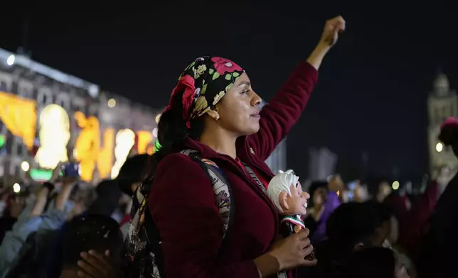 FILE - A supporter of Mexican President Andres Manuel Lopez Obrador holds a doll in his likeness as she listens to him give the annual Independence Day shout from the balcony of the National Palace at the Zocalo in Mexico City, Sept. 15, 2024. (AP Photo/Eduardo Verdugo, File)