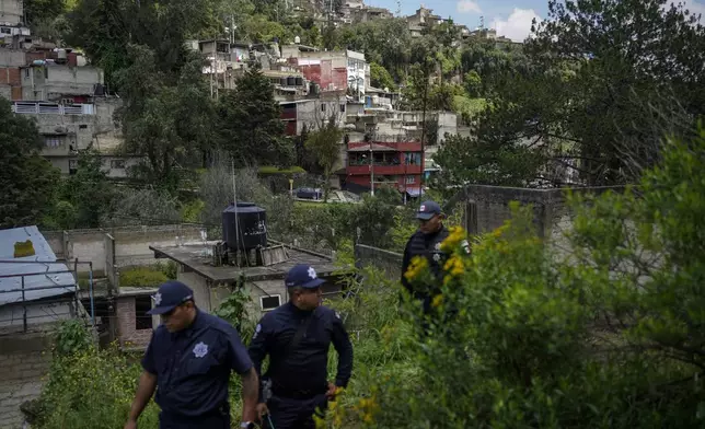 Municipal police officers guard the area where various people died after a rain-induced landslide, in Naucalpan, Mexico, Tuesday, Sept. 17, 2024. (AP Photo/Felix Marquez)