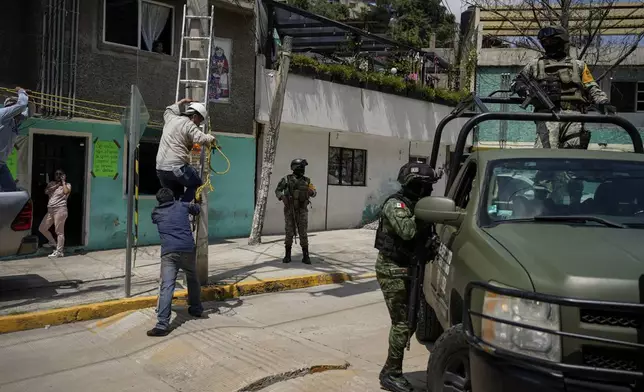 Soldiers guard the area where various people died after a rain-induced landslide, in Naucalpan, Mexico, Tuesday, Sept. 17, 2024. (AP Photo/Felix Marquez)