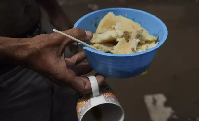 Venezuelan migrant Alí Gómez holds a dish containing tamales and beans at a migrant tent encampment set up along the Vallejo train tracks, in Mexico City, Thursday, July 18, 2024. (AP Photo/Marco Ugarte)