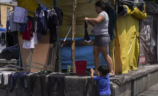 FILE - Venezuelan migrant Osdeigly Granadillo hangs her clothes to dry at a migrant tent encampment set up on the perimeters surrounding the Santa Cruz y La Soledad Catholic parish church, in La Merced neighborhood of Mexico City, July 16, 2024. (AP Photo/Marco Ugarte, File)