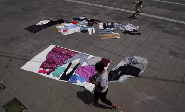 FILE - Clothes are laid out to dry in a courtyard at a migrant tent encampment set up on the perimeters surrounding the Santa Cruz y La Soledad Catholic parish church, in La Merced neighborhood of Mexico City, July 16, 2024. (AP Photo/Marco Ugarte, File)