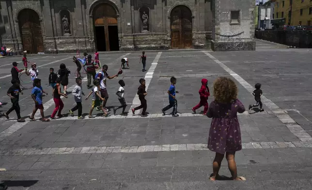 Central America migrant children play on the plaza of the Santa Cruz y La Soledad Catholic parish church, in La Merced neighborhood of Mexico City, Monday, July 8, 2024. (AP Photo/Marco Ugarte)