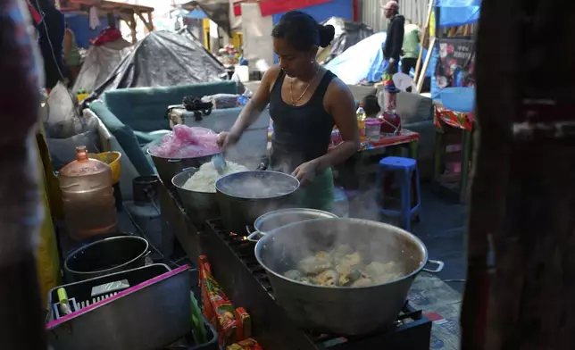 FILE - A Venezuelan migrant prepares chicken and rice to sell, at a migrant tent encampment on the plaza of the Santa Cruz y La Soledad Catholic parish church, in La Merced neighborhood of Mexico City, July 31, 2024. (AP Photo/Marco Ugarte, File)