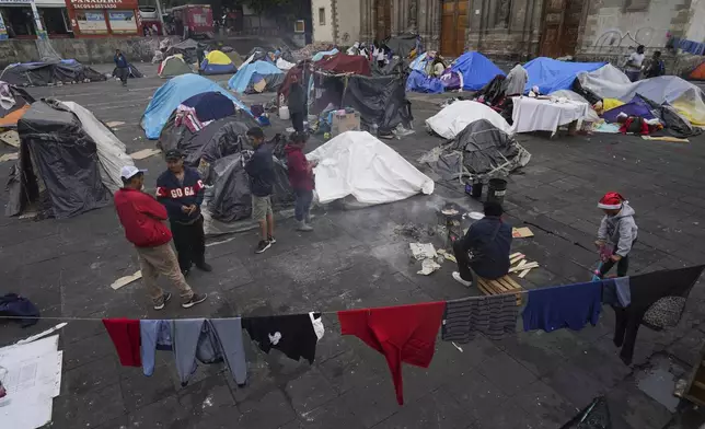 FILE - Migrants gather at a tent encampment set up on the plaza of the Santa Cruz y La Soledad Catholic parish church, in La Merced neighborhood of Mexico City, Dec. 26, 2023. (AP Photo/Marco Ugarte, File)