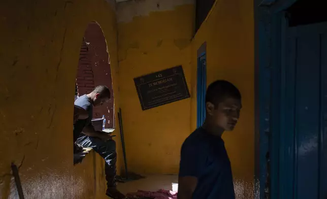 First-year student Jesus Castro Rafaela walks inside the Raúl Isidro Burgos Rural Normal School where a sign memorializes Julio Cesar Mondragon Fontes, a student who died on the night that 43 fellow students went missing, in Ayotzinapa, Guerrero state, Mexico, Monday, Aug. 26, 2024. (AP Photo/Felix Marquez)