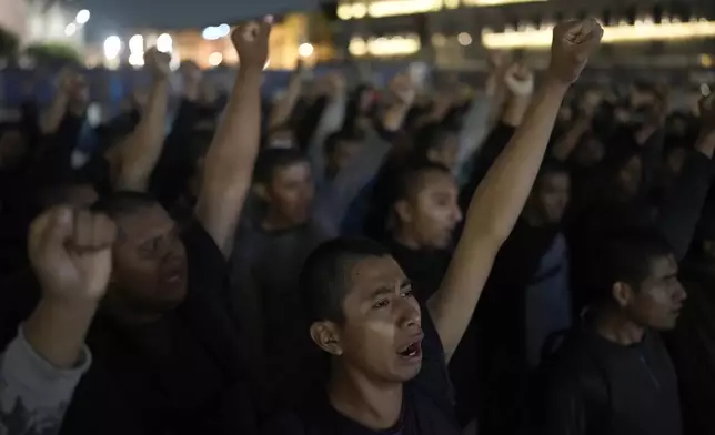 Youths chant, raising their fists in unison, as they take part in a demonstration marking the 10-year anniversary of the disappearance of 43 Ayotzinapa rural teacher's college students, in front of the National Palace in Mexico City, Thursday, Sept. 26, 2024. (AP Photo/Eduardo Verdugo)