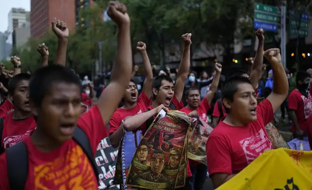 Youths chant and raise their fists in unison as they take part in a demonstration marking the 10-year anniversary of the disappearance of 43 students from an Ayotzinapa rural teacher's college, in Mexico City, Thursday, Sept. 26, 2024. (AP Photo/Eduardo Verdugo)