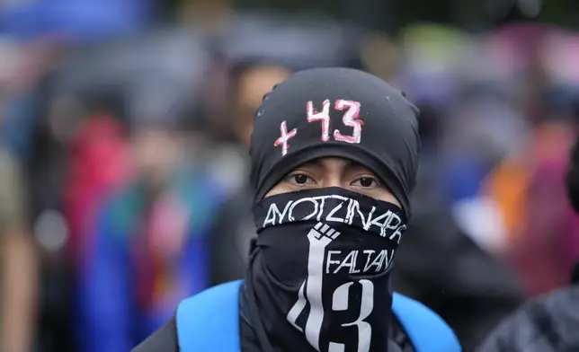 A masked youth takes part in a demonstration marking the 10-year anniversary of the disappearance of 43 students from an Ayotzinapa rural teacher's college, in Mexico City, Thursday, Sept. 26, 2024. (AP Photo/Eduardo Verdugo)